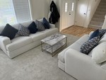 Two beige/gray sectionals in a living room with a coffee table and pillows